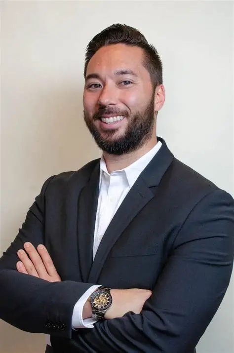 Sean Yoshikawa, life science and MedTech branding advisor, smiling with arms crossed in a dark suit jacket and white shirt